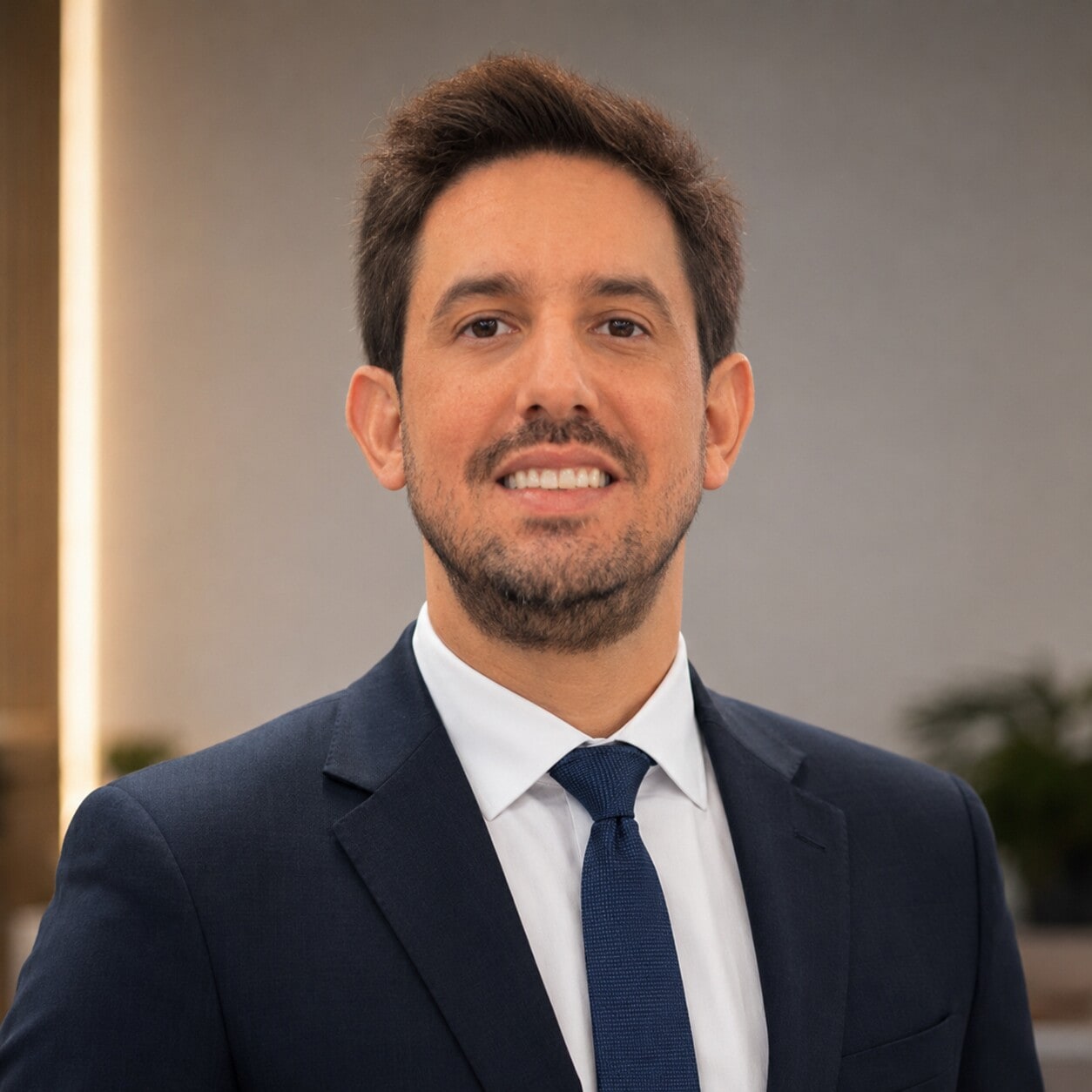 Retrato profissional de Leonardo Veras, de terno azul-marinho e gravata, em ambiente corporativo.